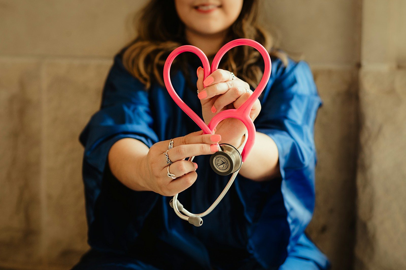 woman in scrubs holding heart shaped stethoscope