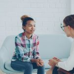Two women talking in a modern office setting.