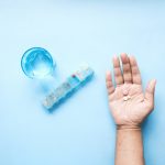 person holding pink and white medicine pill